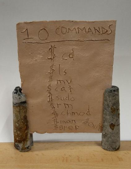 The artwork is a block of clay measuring 20x15x2 cm.  Ten different Unix commands ($ cd, $ ls, $ mv, ...) are engraved in the clay block. The clay block stands on two 10 cm high clay supports.