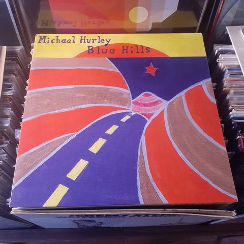 Album cover features a painting of a road passing between striped hills.