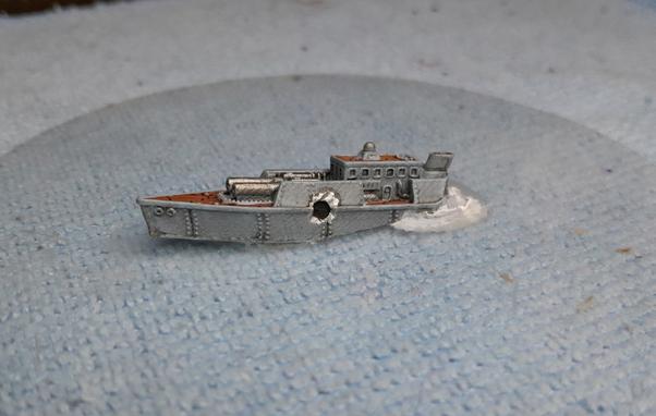 miniature wargame ship sinking with a hole blasted in it