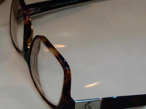 Set of well worn tortoiseshell glasses inverted on a white table, mismatched hardware