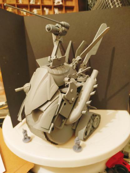 A grey primed model of a SF styled (built at 15mm/20mm scale) "super tank". With small military SF scale figures surrounding it. This was an attempt at trying something slightly different, rather than the usual tank-like turret gun, I wanted to go for the more Marvin the Martian style pop out laser on an articulated arm. The arm came from a old broken miniature clip on bookmark lamp. And the huge exhaust on the side is a milk carton handle, perforated by old plastic straws.