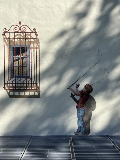 A mural depicting a child with a fishing rod that’s snagged his line on the iron security grill of a window.