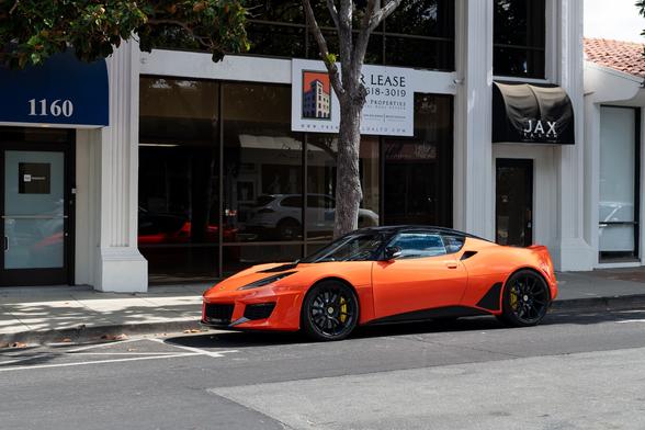 Orange exotic sports coupe, street parked.