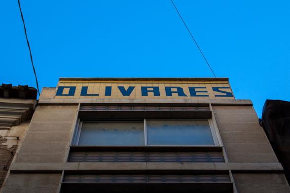 Top of the building. Saying Olivares. The building style seems like 60s, 70s. In Plateria st. Murcia.