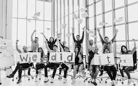 Young people inside glass building celebrating with text "we did it"