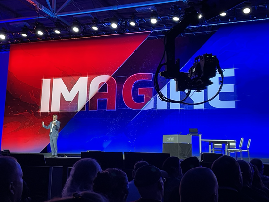 Bernard Charles - Dassault Systemes COB on stage in front of display with word IMAGINE behind him and a panning camera on a boom in the foreground