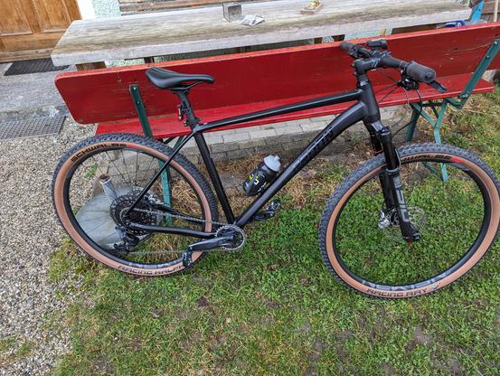 Mein neues Crosscountry Mountainbike (XC) der Marke Radon Jealous AL 10.0 SL in schwarz steht vor einer Gartenbank