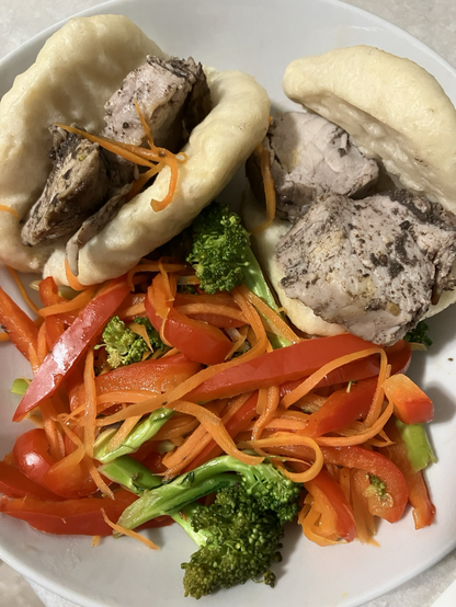 Pork tenderloin medallions in two bao with red peppers, carrots and broccoli