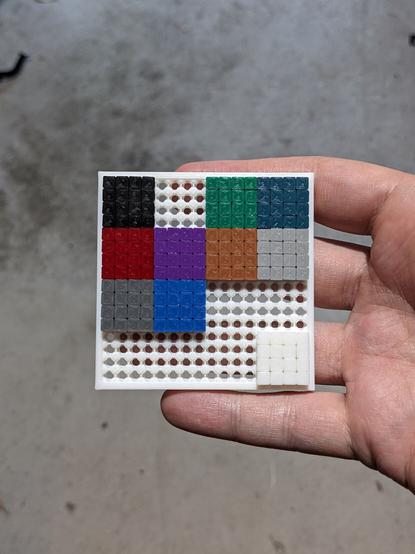 A photo of a small 3D printed frame, which holds a series of also 3D printed coloured tiles.