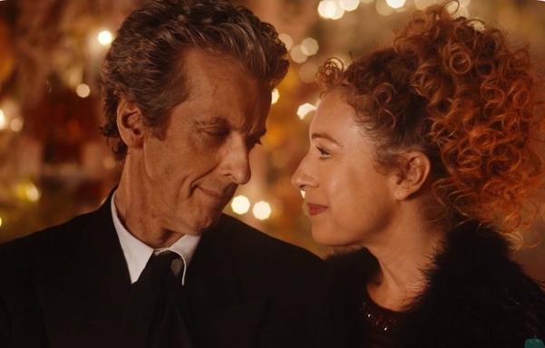 The 12th Doctor (Peter Capaldi) and River Song (Alex Kingston), gazing lovingly at each other. Twinkling golden fairy lights behind them. They're both wearing formal wear (black).