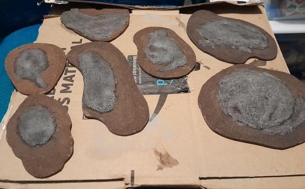 miniature wargaming terrain.  rocky islands on a cardboard box, mostly painted sand over hardboard shapes