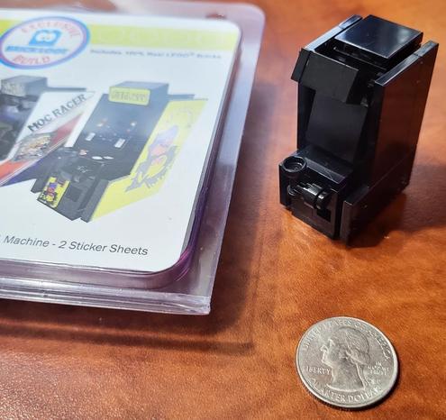 A small black assembled LEGO arcade with no decals yet. It's a custom from Brickloot. Next to its case showing it with decals. And a quarter for scale.