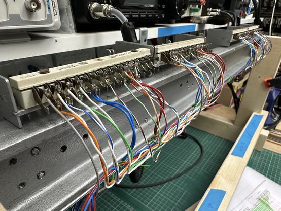 Cast iron shelf with lots of solder tag connections attached. Many coloured wires are connected to the solder tags