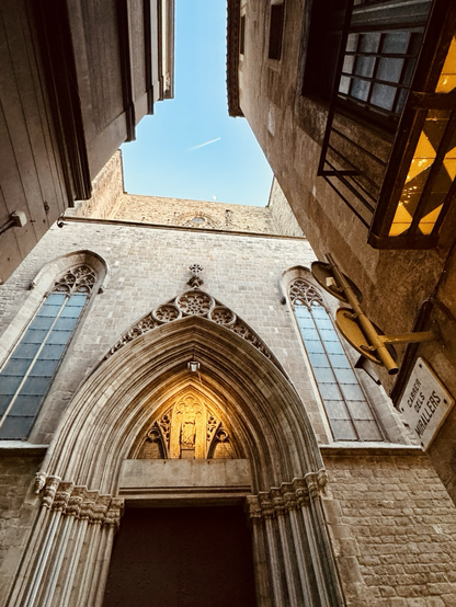 Catedral de Santa Maria del Mar from Carrer dels Mirallers with a quarter-moon visible and a plane flying over.