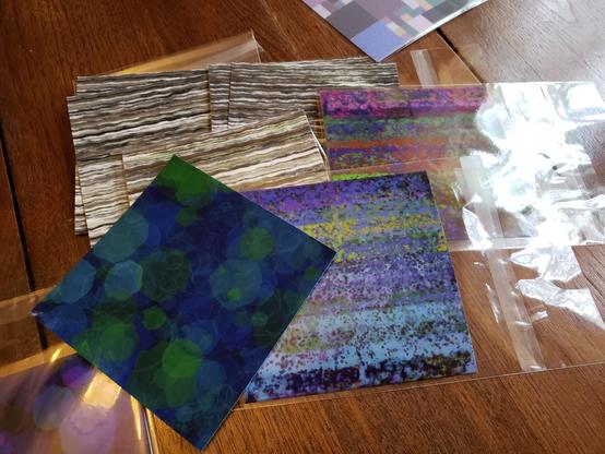 Some test prints, on fine art paper, haphazardly arranged on my table. The prints are all of abstract patterns.