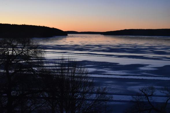 Sunleviĝo super glacia lago en Svedio