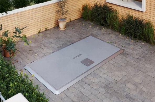 A paved front garden with a large grey hatch flush with the ground.