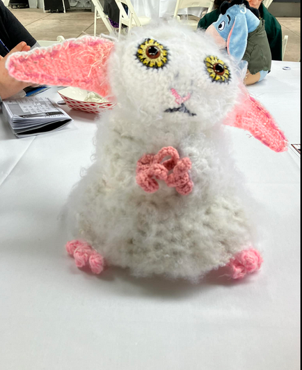 Crocheted figure, based on the Meep in Doctor Who, a white fluffy character with large yellow eyes and large pointed pink ears, also has pink hands and feet