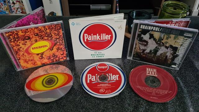 Three cd cases with their cd's in front of them. They are all by the band Brainpool. From left to right: Soda, Painkiller & Stay Free.