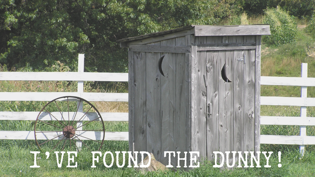 A wooden outhouse in front of a white picket fence. The title of the post ‘I’ve found the dunny!’ Is written across the bottom