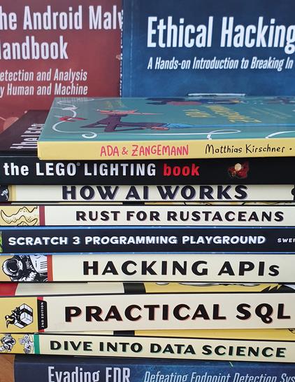 Ein Stapel Bücher von "No Starch Press". Man erkennt Titel wie "How AI Works", "Rust For Rustaceans", "The LEGO Lighting Book", "Hacking APIs", "Ethical Hacking" und mehr.