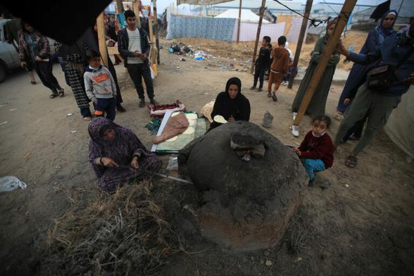 A photograph of women baking bread in a refugee camp in Gaza.
