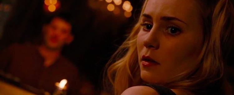 A woman turning to look over her shoulder as the candlelit room seems to tilt.