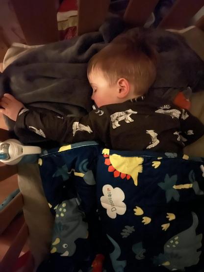 A blond toddler, sleeping peacefully on his front under a blanket
