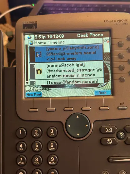 an old IP telephone with a big but crusty screen, showing a list of items. the items are posts from fedi, with the username and a part of the post visible. above a button to the bottom left there's a label with the words "New Post" and to the right, a button that says "Back"