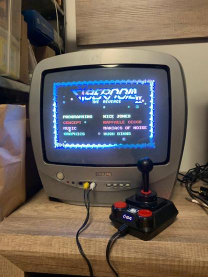 C64 DTV game console connected to Philips 14" CRT television set, showing title screen from Cybernoid II game with credits. Both C64 DTV and this Philips TV were released in 2003.