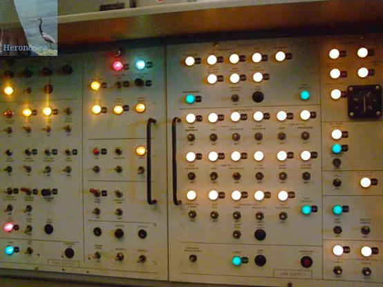 An indoor photograph of a light indicator panel for the fueling of a rocket. There are rows of mostly white lights, with some green and red and a gray background with black labels.