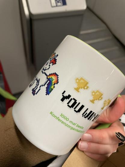 DHd2022 Kaffeetasse Rückseite. Mit Pixelart-Regenbogen-Einhorn, drei Pokalen und Text You win! 1000-mal beste Konferenzorganisatorin