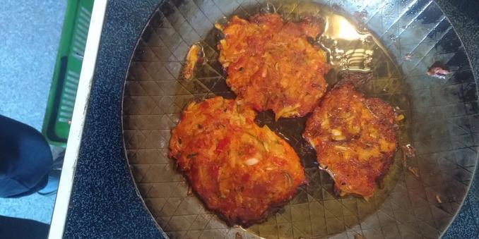 Drei Reibeplätzchen in einer Pfanne auf dem Herd.