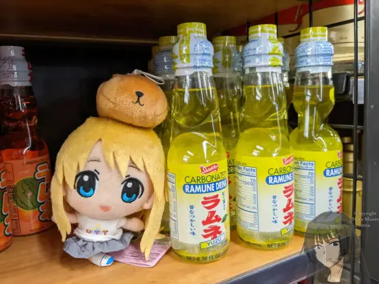 Mugi plushie stands next to yellow bottles of yuzu soda