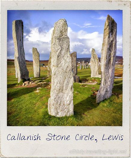 Square photo of a tight group of tall, slim monoliths, set in grass, and with more stones behind. Set in a scuffed Polaroid type frame.
