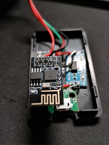 Inside the push button.
You see a ESP01 module in focus. Beneath you can see a AMS1117 step-down-module and a USB port, both glued to the bottom. In the background some wires in red, green and black leave the picture