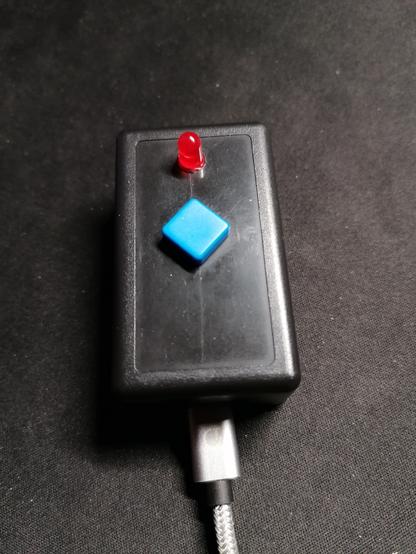 A picture of the actual "front-end" of the button. You see a black box with a red LED overhead. Instead of only parts, you can see the whole LED.
Beneath there is a blue square rotated by about 45°, so edges are pointed to the flat sides of the rectangular box