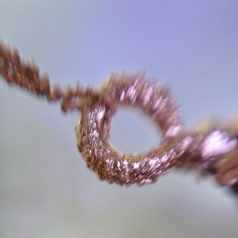 An extreme closeup of a copper ring with a bumpy texture.