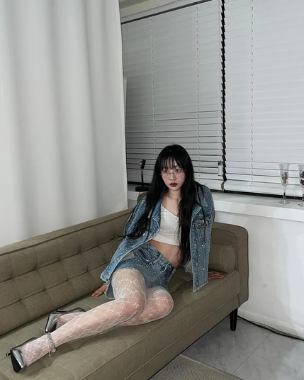Kpop idol Yves reclining on a sofa.