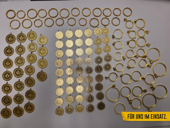 Auf einem Tisch liegen die gefundenen Schmuckstücke aus Gold. Neben Ringen wurden hier auch Schmuckmünzen geschmuggelt.