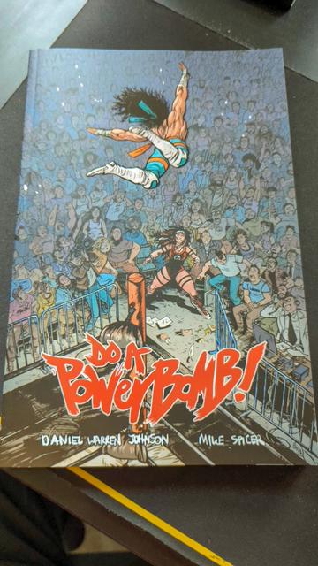 Trade paperback for Daniel Warren Johnson's Do a Powerbomb. This is the front cover of the TPB showing a wrestler leaping from the top rope with the aim of bodyslamming their opponent