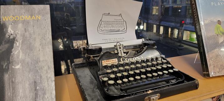 Ancient typrlewriter displayed among photography books, overlooking noghttime city streets