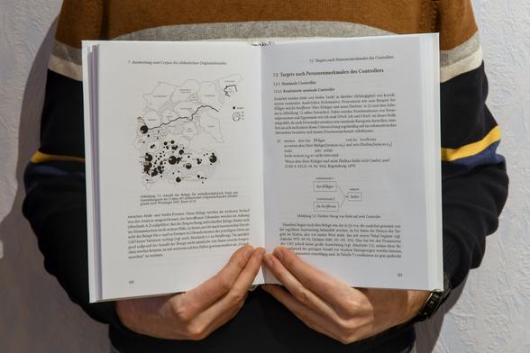 Aufgeschlagenes Buch mit Karte und Text vor dem Bauch gehalten