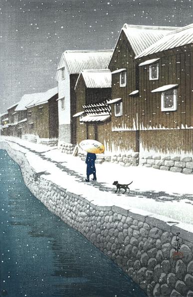 A pedestrian and their dog walk along a canal on a snowy winter's day. In the foreground, cold-looking water flows along a canal, contained by an embankment of irregular stones. On top of the embankment, a pedestrian in dark clothing walks along a rough track in the snow, carrying a bamboo umbrella as protection against the poor weather; just behind them, a small dog follows along. To the right, industrial-looking wooden buildings crowd close together, looming over the canal. Above, the sky is steely gray and overcast. Snow lies across the ground and the rooftops of the buildings, and continues to fall across the scene