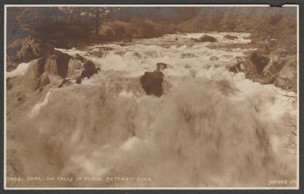 Sepia real photographic postcard showing a view of the Swallow Falls in flood at Betws-y-Coed in Caernarfonshire in Wales.
Published by Judges Ltd, Hastings, No 5482, 1920.
Postally unused.
Fairly good condition, with slight corner bumps, but with large chip to right top edge, otherwise good.