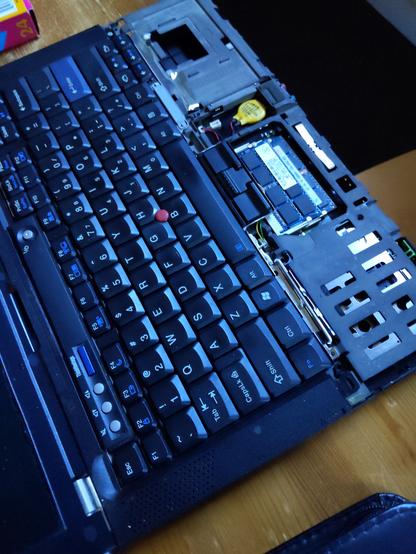 A partially disassembled thinkpad t400. It's missing it's palm rest, which is currently having a crack glued back together.