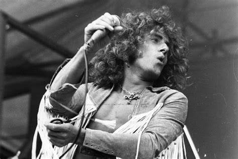 Roger Daltrey holding a mic, long hair, black and white