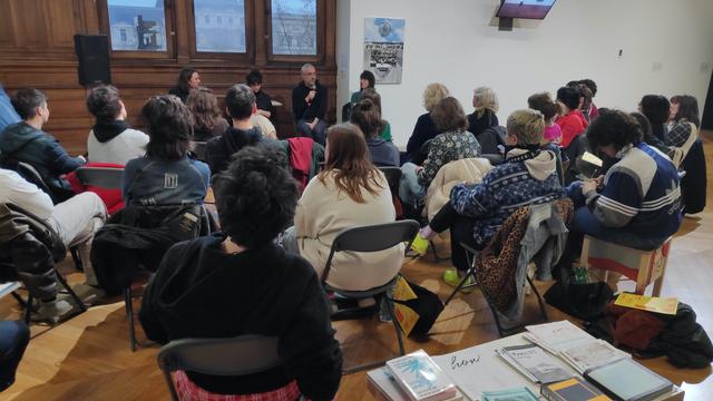 Photographie de la rencontre, vue de derrière le public. On voit une trentaine de personnes de dos, faisant face aux quatre interventant·es. De gauche à droite, on a Théo Pall, Margot Bernard, Vincent Romagny et Marie Preston. La rencontre se déroule dans une salle avec un beau parquet, trois grandes fenêtres au travers desquelles on aperçoit le Louvre au loin, et on voit aussi des cimaises blanches sur lesquelles sont accrochées des oeuvres d'art.