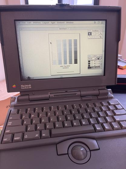 Ryza running PageMaker, an old desktop publishing app, showing some toolboxes and a page view of a bunch of color calibration blocks. she's clean and relatively unscuffed for a 30-year-old machine, but her screen is fading to black at the corners.
