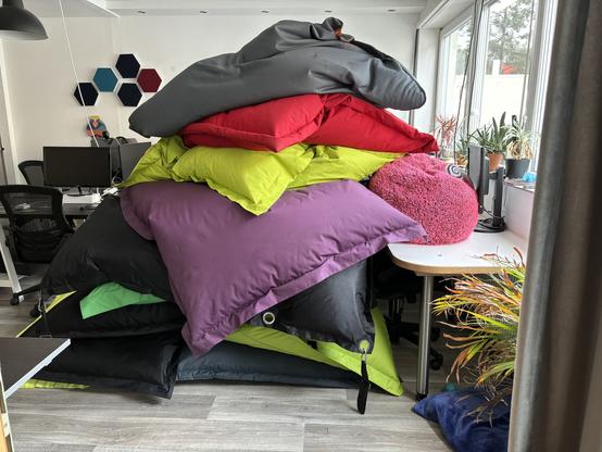In einem Coworkingspace mit Schreibtischen links und rechts sind ca. 8 Sitzsäcke aufeinandergestapelt und reichen fast bis zur Decke.